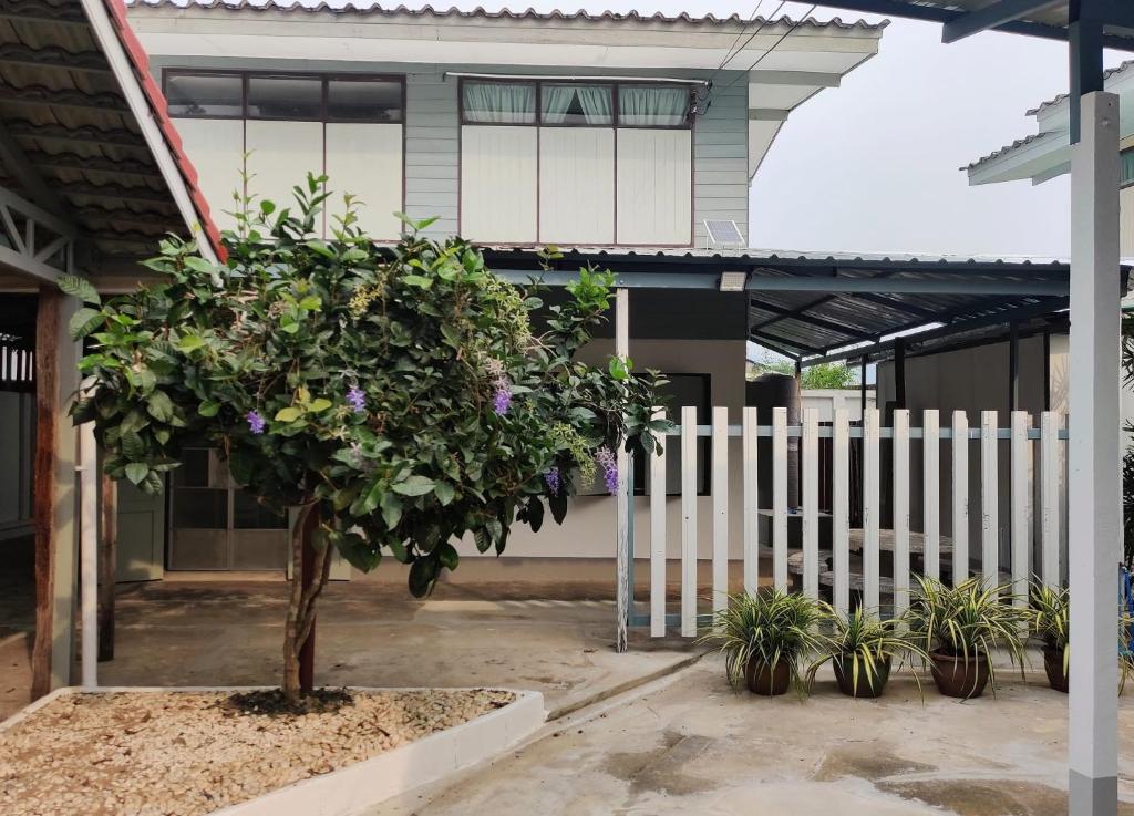 a tree in front of a building with a fence at The Neighbors in Chanthaburi