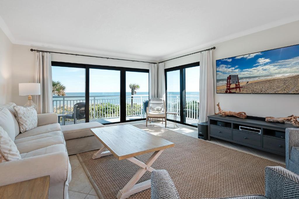 a living room with a couch and a table at Take in the oceanfront corner views located on the no-drive beach! in New Smyrna Beach
