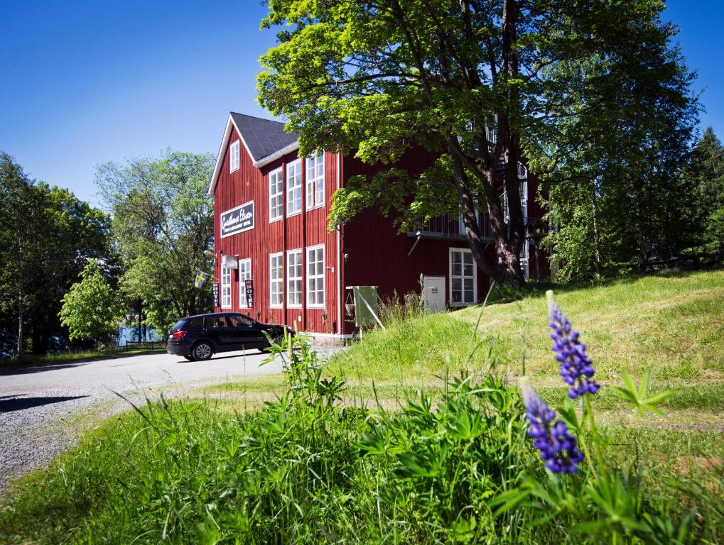 un bâtiment rouge avec une voiture garée devant lui dans l'établissement Guesthouse Eleven Hotel, à Arvika