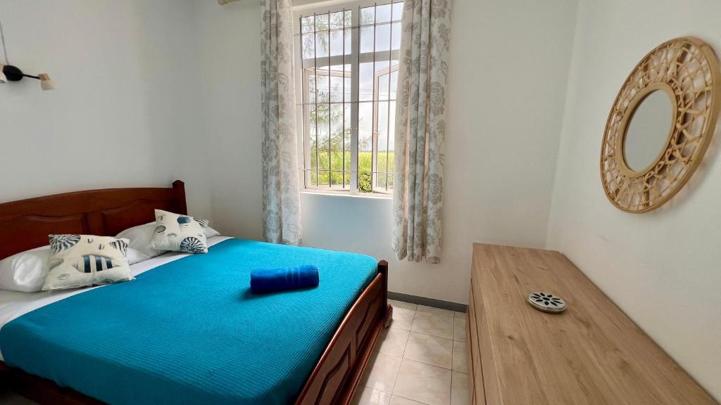 a bedroom with a blue bed and a window at Lakaz Bigorno - Villa 200m from Blue Bay Beach in Blue Bay
