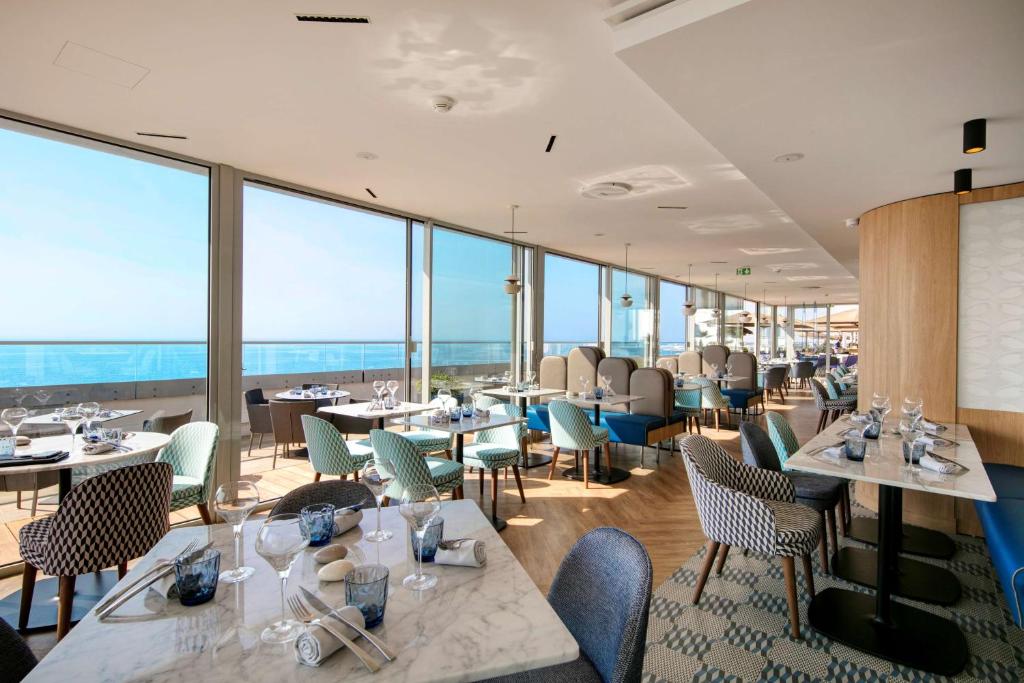 un restaurante con mesas, sillas y ventanas grandes en Radisson Blu Hotel Nice, en Niza
