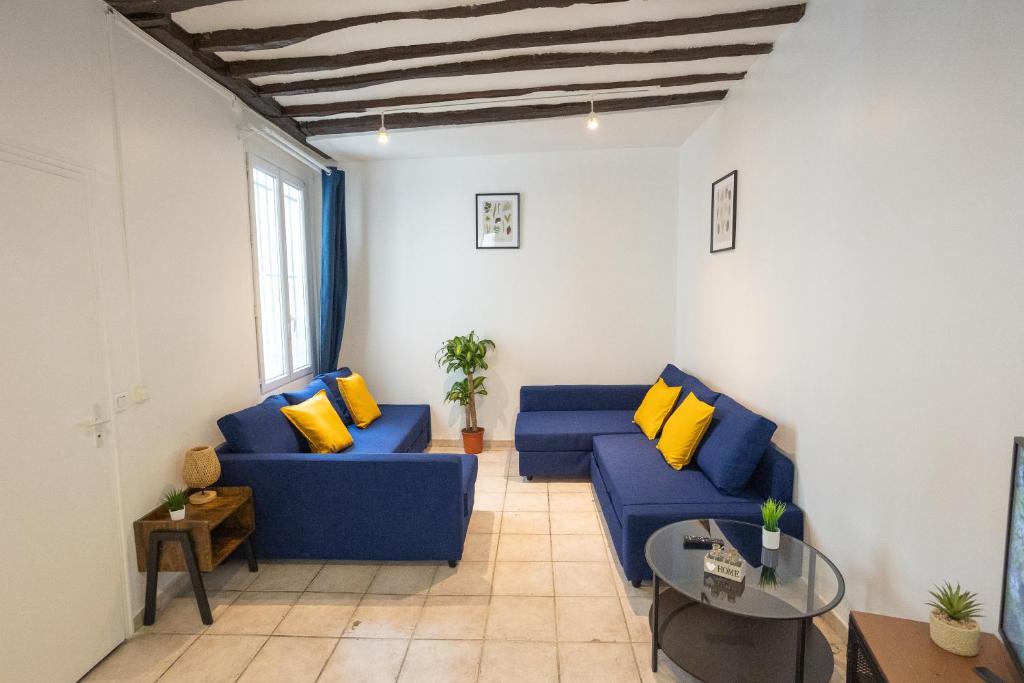 - un salon avec des canapés bleus et des oreillers jaunes dans l'établissement Studio en plein coeur de Paris deuxieme arrondissement Quartier Montergueil Chatelet, à Paris