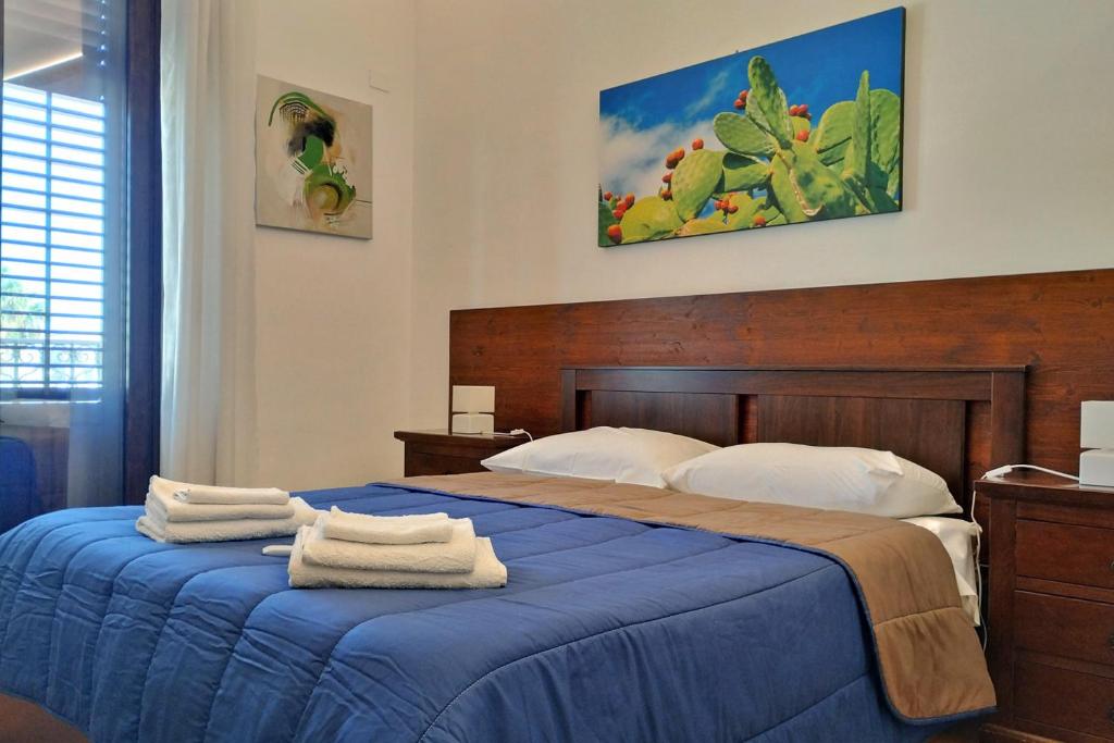 sypialnia z niebieskim łóżkiem i ręcznikami na nim w obiekcie Porta Carini Residence w mieście Palermo