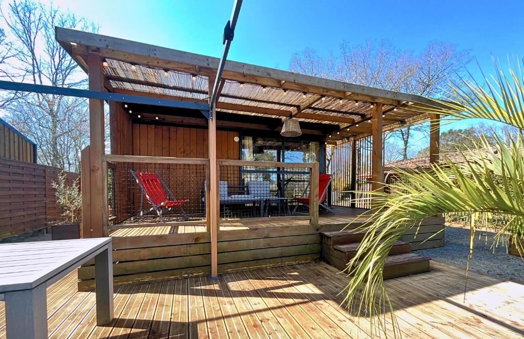Una terraza de madera con una mesa y sillas. en Le Ti Bois, Chalet tout équipé vue forêt, 5 prs, en La Teste-de-Buch