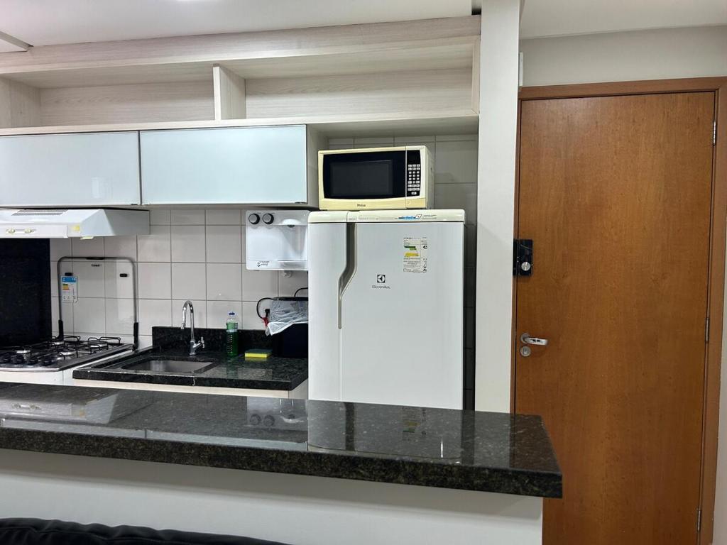 a kitchen with a microwave on top of a refrigerator at Flat completo com linda vista in Palmas