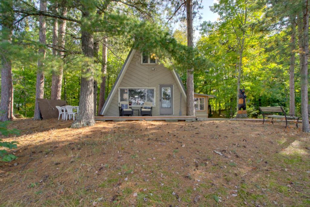 a cabin in the woods with a picnic table and benches at Quiet Deer River Cabin with Dock and Lake View! in Deer River