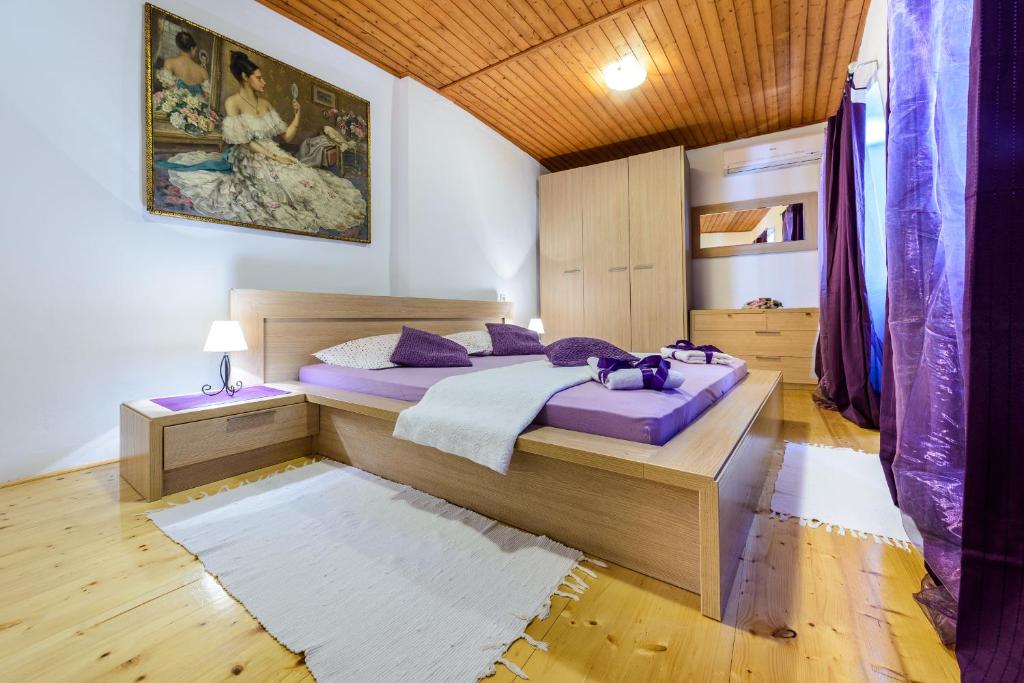 um quarto com uma grande cama de madeira com almofadas roxas em Apartman Antonio em Dubrovnik