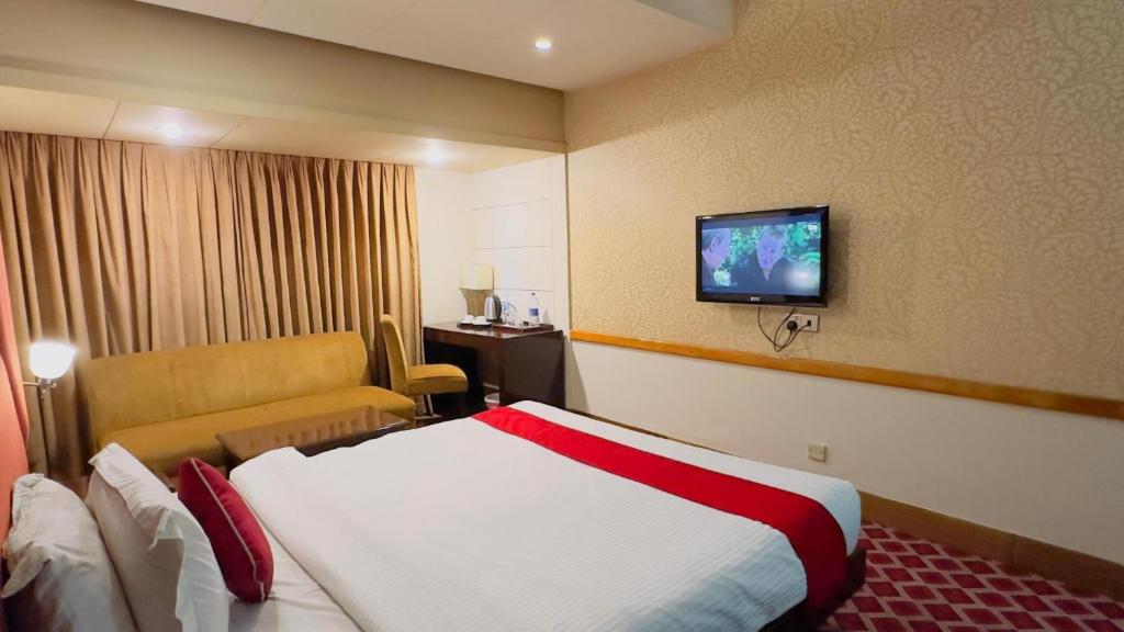 a hotel room with a bed and a tv on the wall at West Park Inn in Dhaka
