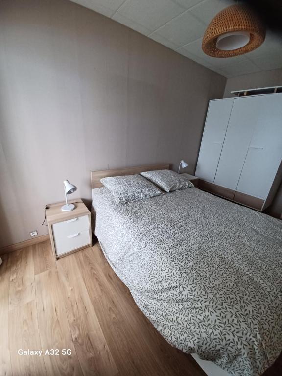 een slaapkamer met een groot bed en een nachtkastje bij Le Mathgo in Saint-Hilaire-de-Riez