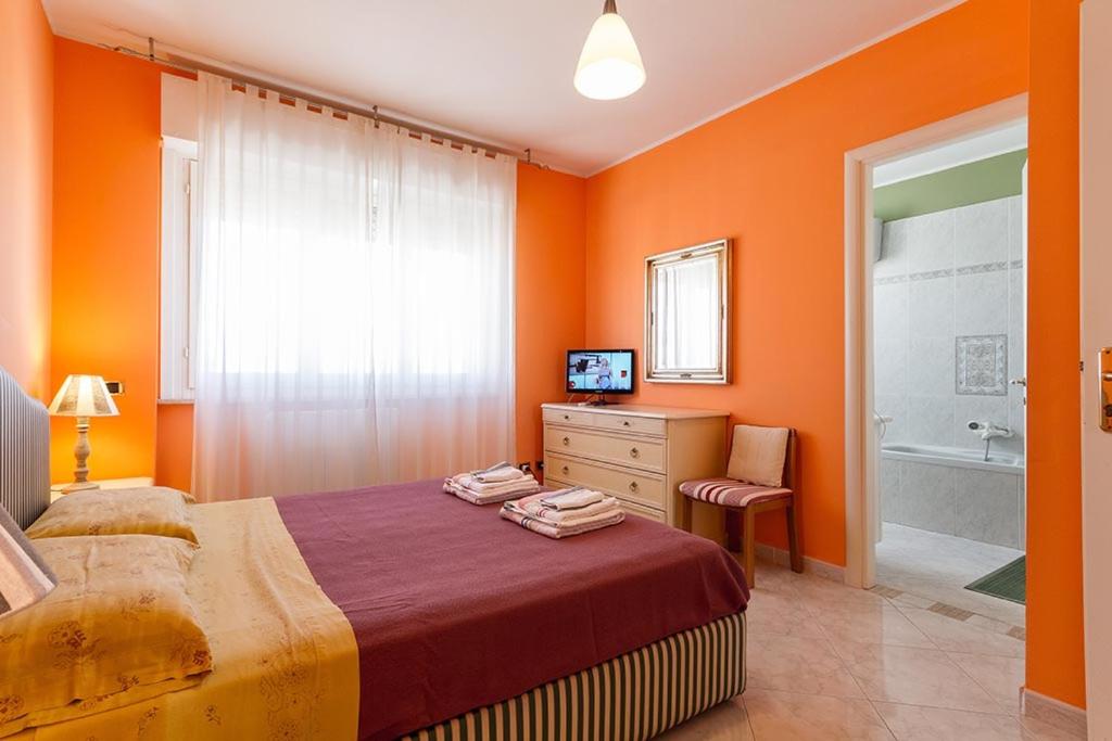 een slaapkamer met oranje muren en een bed en een bad bij B&B Mareya in Cagliari