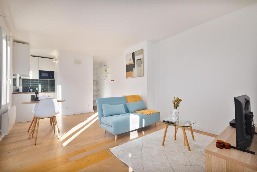 un salon avec un canapé bleu et une cuisine dans l'établissement Appartement lumineux proche de Paris et des transports, à Montreuil