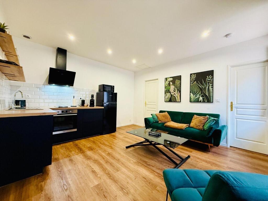 un salon avec un canapé vert et une cuisine dans l'établissement Les Logis d'Esmeralda-Des appartements au charme intemporel, à Romorantin-Lanthenay