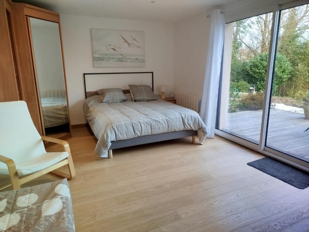 een slaapkamer met een bed en een glazen schuifdeur bij Les hortensias in Lannion