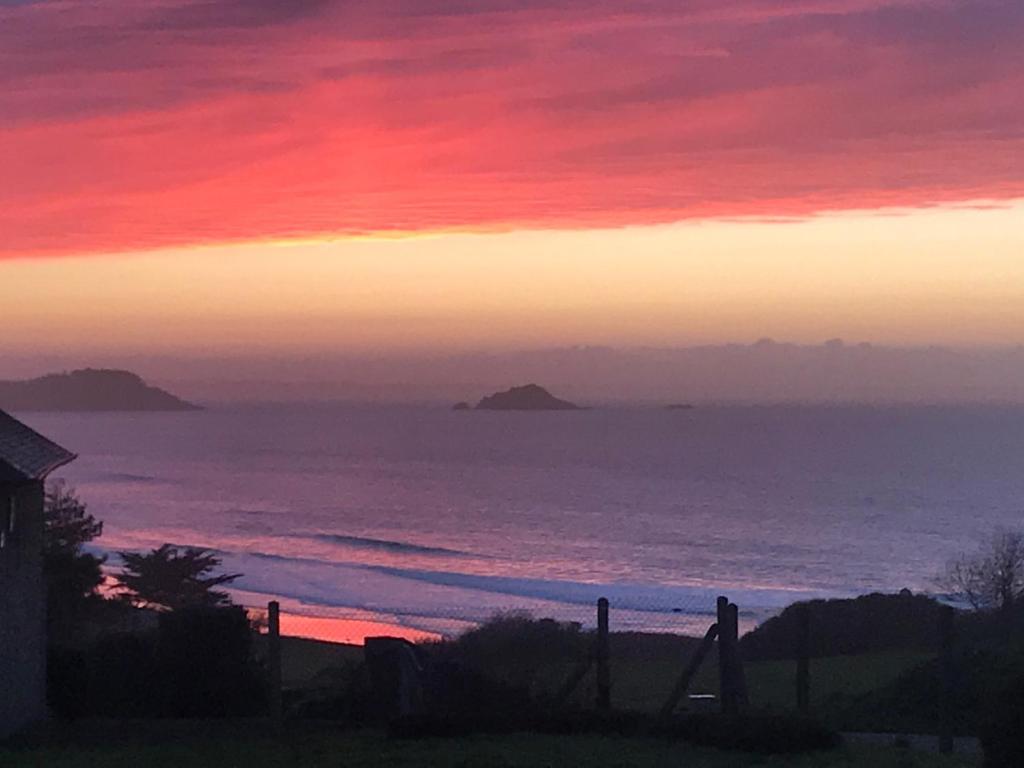 un coucher de soleil sur l'océan avec une personne sur une balançoire dans l'établissement Maison face à la mer, à Erquy