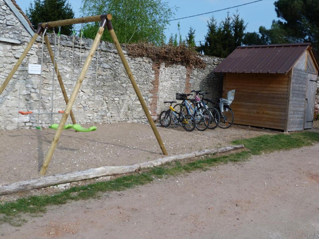 a swing set with bicycles parked next to a stone wall at Les Gites De Colliers in Muides-sur-Loire