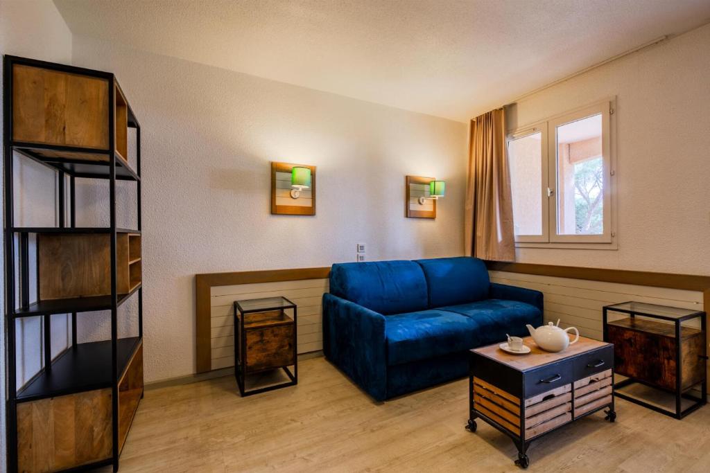 un salon avec un canapé bleu et une table dans l'établissement Résidence Saint-Raphaël Valescure - maeva Home - Studio 4 Personnes Sélection MAE-5437, à Valescure