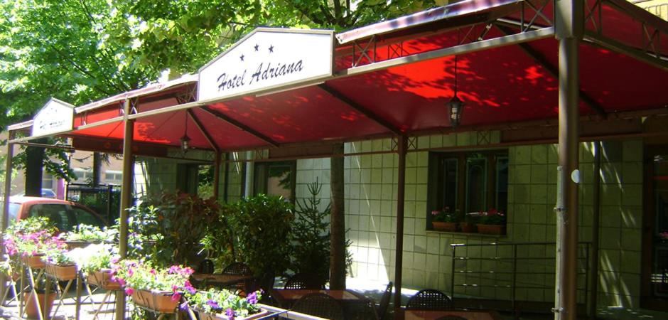 un ristorante con tenda rossa e alcune piante e fiori di Hotel Adriana ad Abbadia San Salvatore