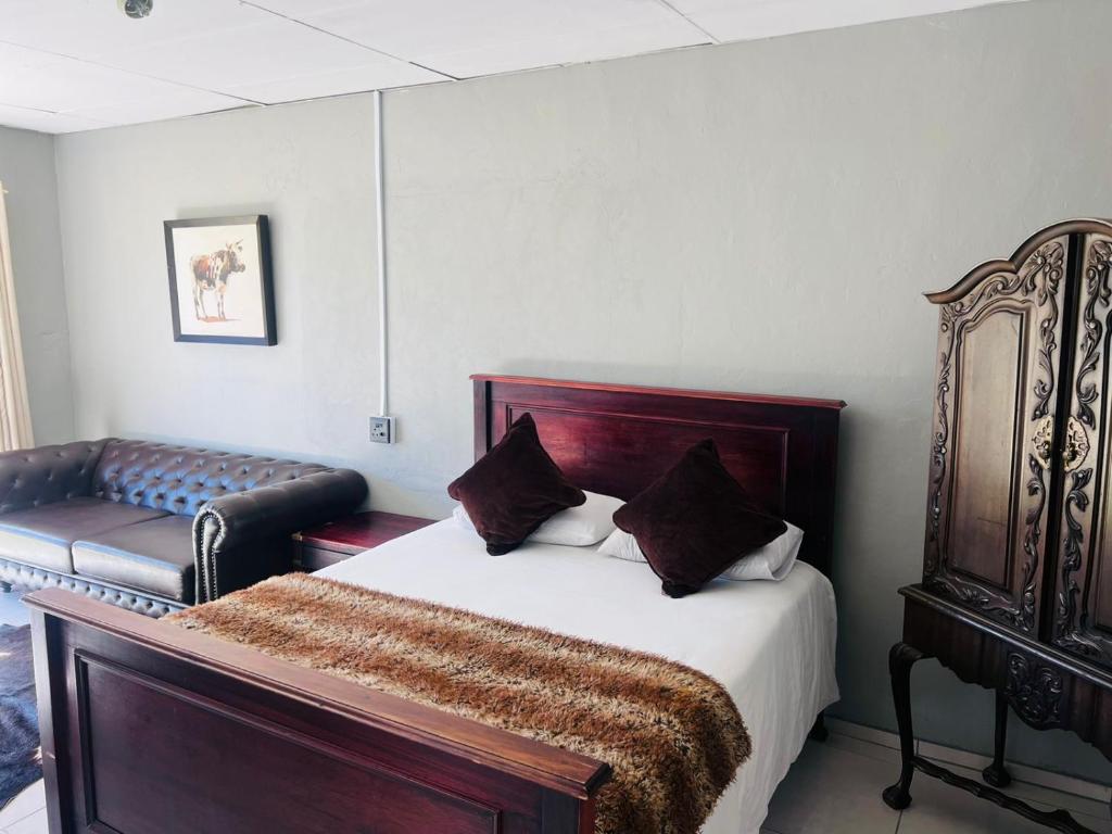 a bedroom with a bed and a bench in it at Signature Guesthouse in Ventersburg