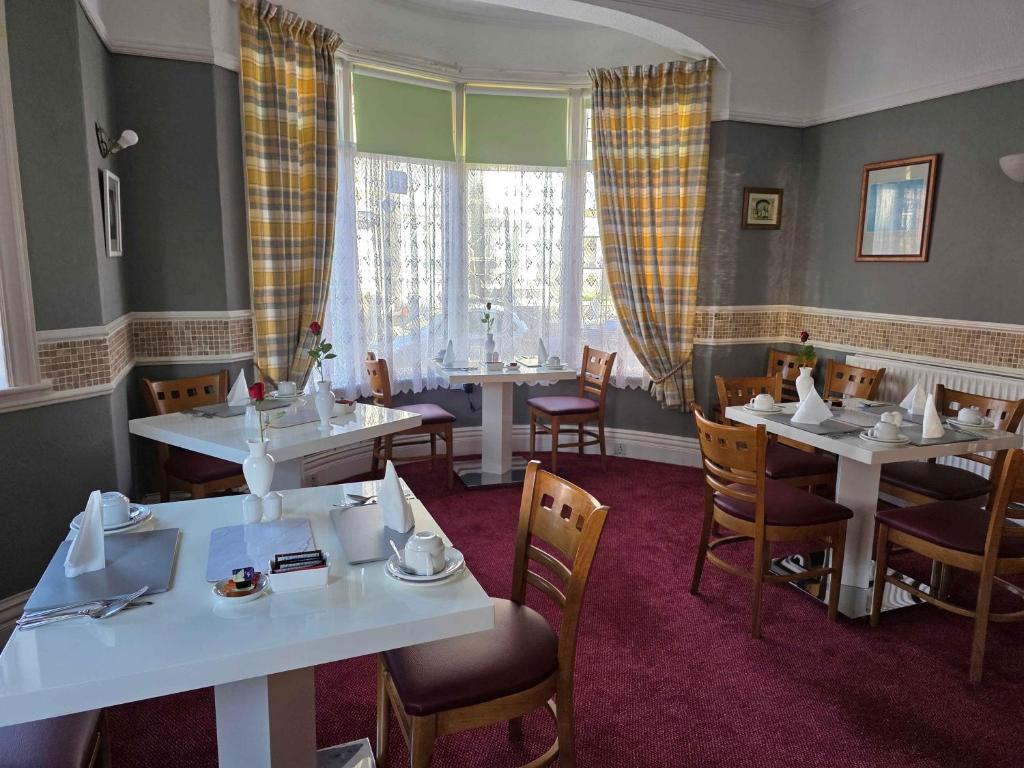 a dining room with white tables and chairs at Collingwood Hotel in Blackpool