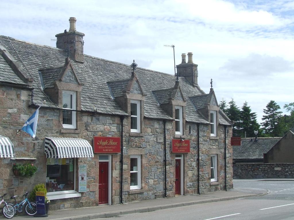 - un vieux bâtiment en pierre sur le côté d'une rue dans l'établissement Argyle Guest House, à Tomintoul