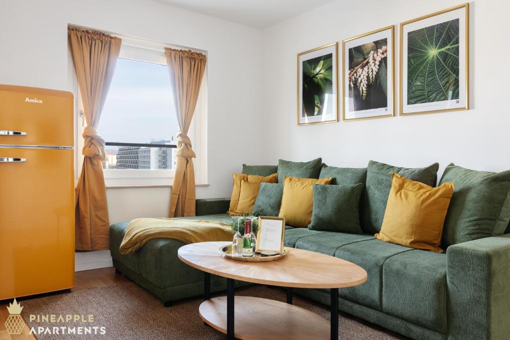 ein Wohnzimmer mit einer grünen Couch und einem Tisch in der Unterkunft PINEAPPLE APARTMENTS - Zwinger XI - 64qm in Dresden
