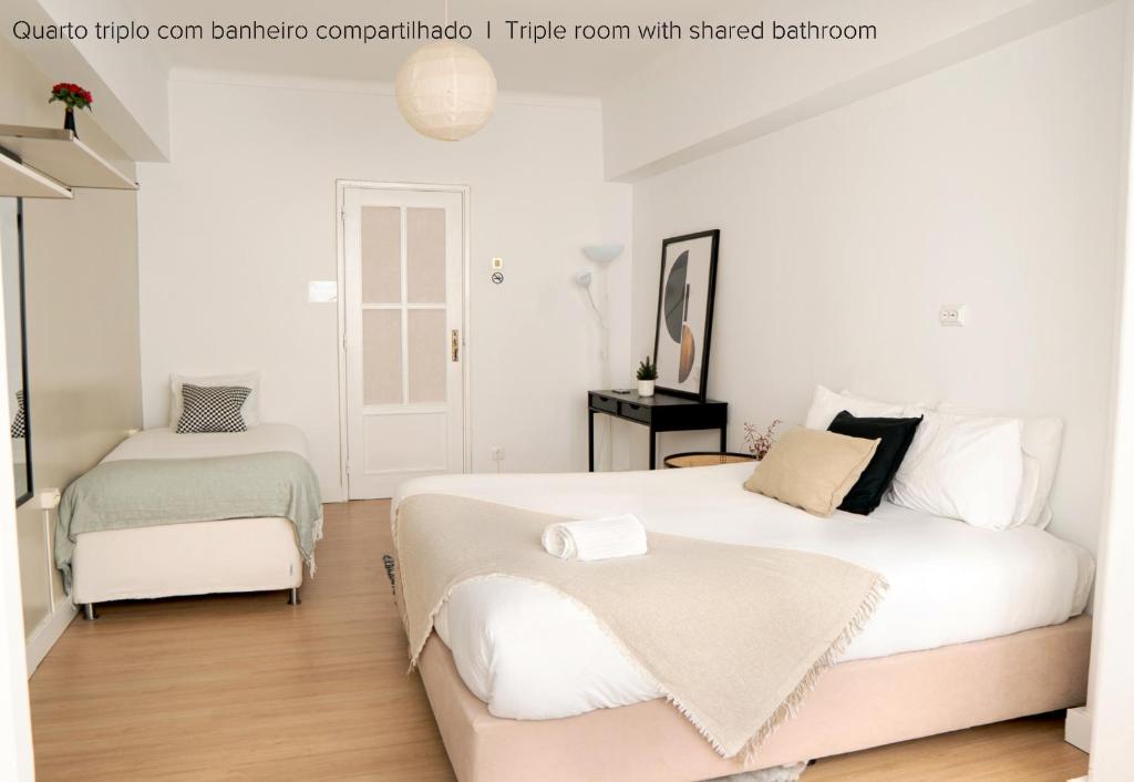 2 camas num quarto com paredes brancas e pisos em madeira em Soar Home I Urban Nest - Near Airport & Green Park em Lisboa