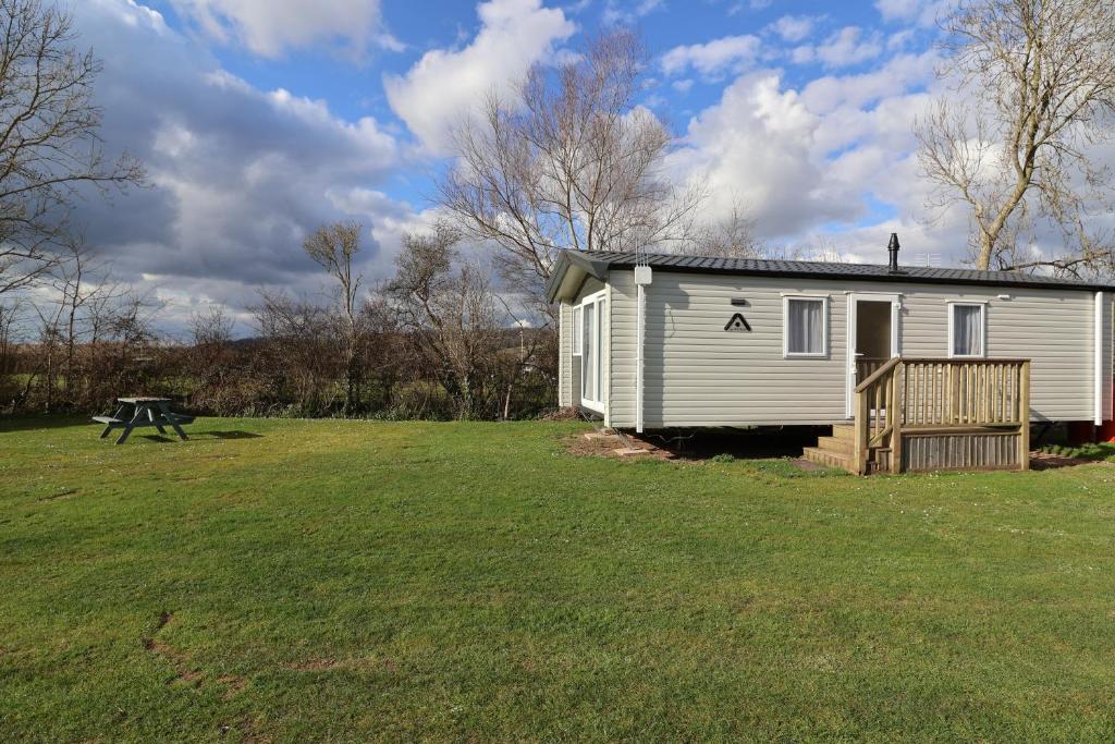 a small white house in a grassy field at The Roost - Family Friendly caravan near Glastonbury & Street in Compton
