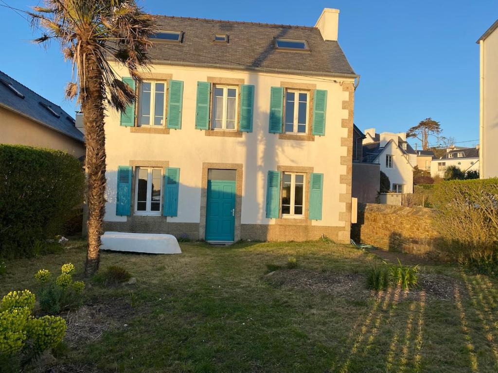 une maison avec des volets verts et un palmier dans l'établissement Water front Tradition breton fisherman house, à Carantec