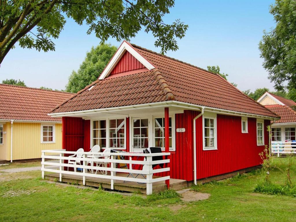 a red house with a white fence in front of it at Holiday Park Markgrafenheide Markgrafenheide in Markgrafenheide