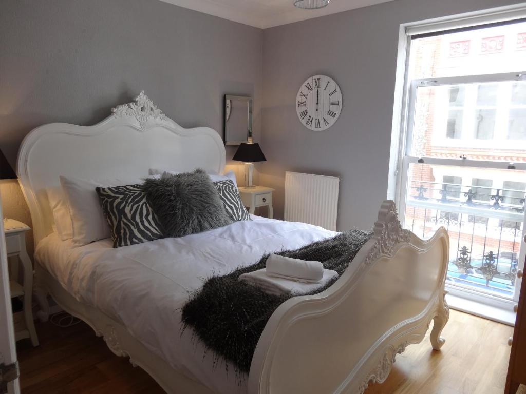a white bed in a room with a clock on the wall at Burlington Beach Apartments in Brighton & Hove