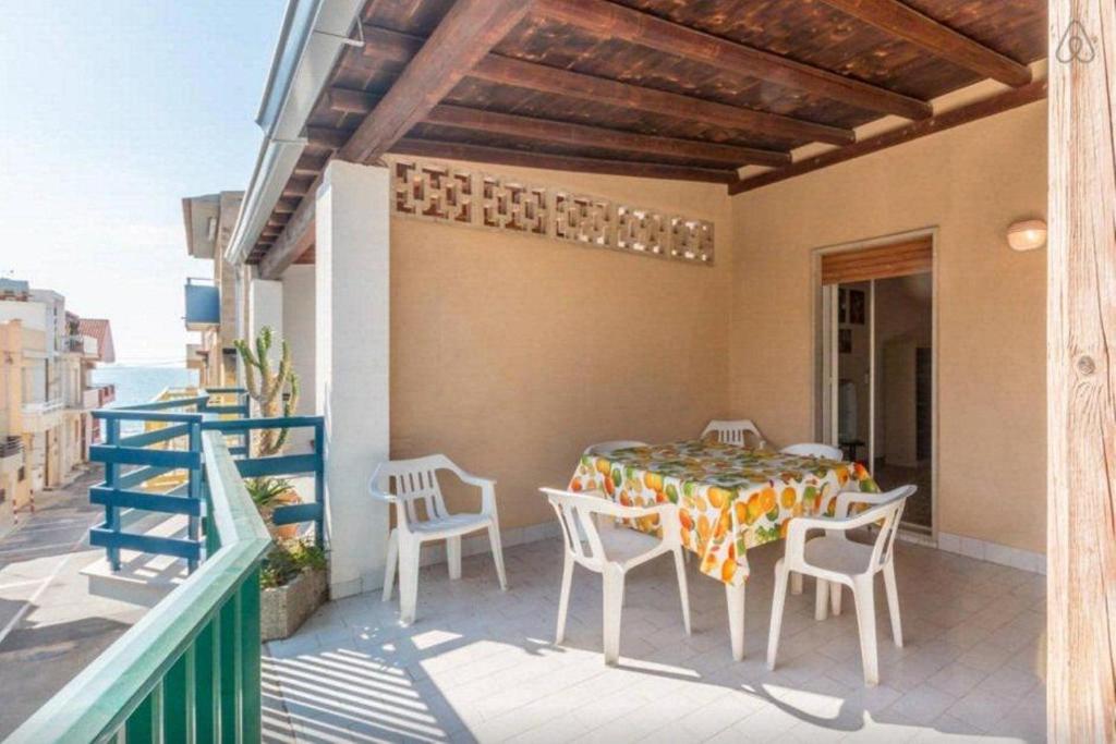 eine Terrasse mit Tisch und Stühlen auf einem Balkon in der Unterkunft Ulisse apartment on the sea in Punta Secca