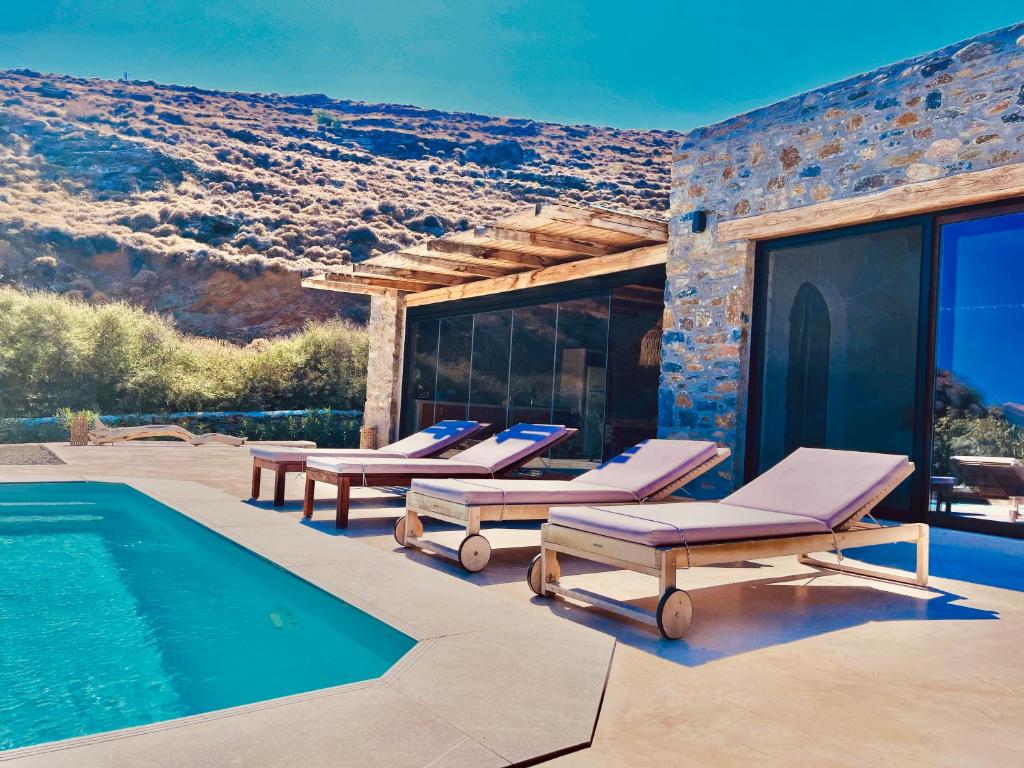 a group of lounge chairs next to a swimming pool at Kythnian Retreat in Kithnos