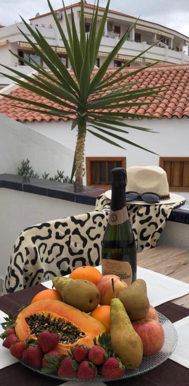 a plate of fruit on a table with a bottle of wine at Olimpus Apart Leasure in Costa de Adeje