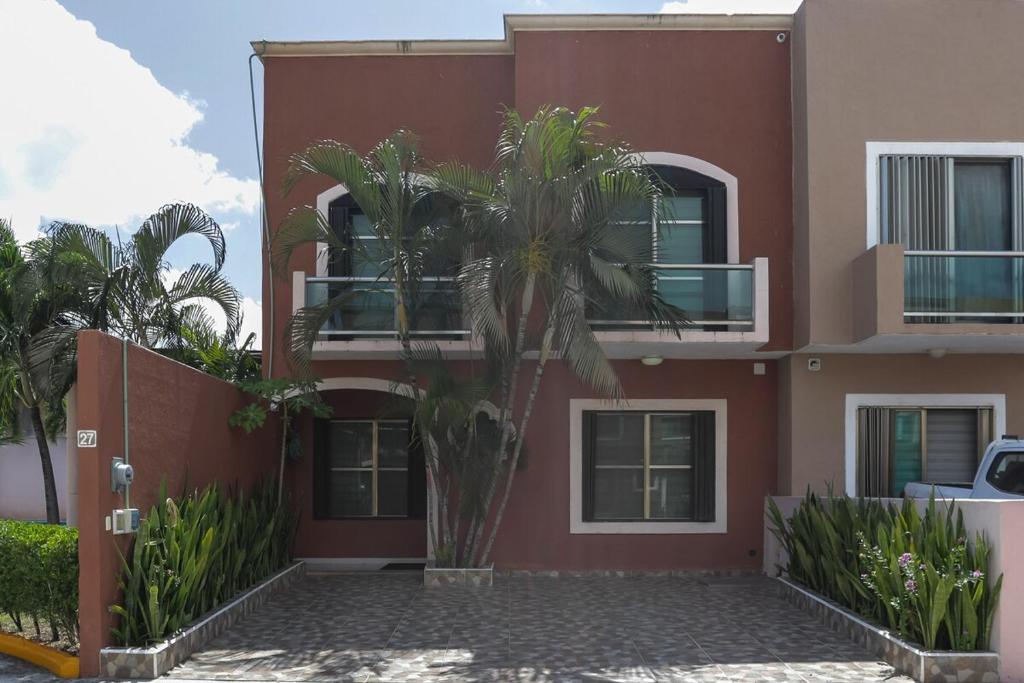 a red building with a palm tree in front of it at Downtown Villa for 7 guests, access to pool! in Cancún