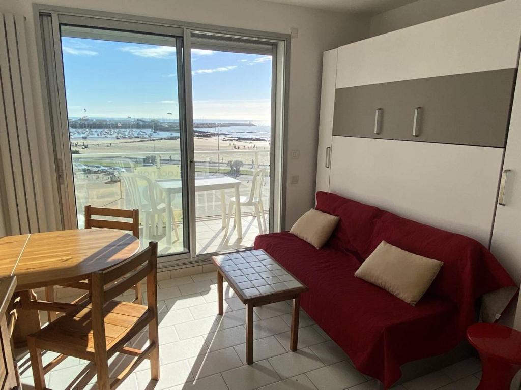 un salon avec un canapé rouge et une table dans l'établissement Résidence Les Marines - Location de Vacances - PORNICHET - T2 FACE MER - QUARTIER OCEANES MAE-2891, à Pornichet