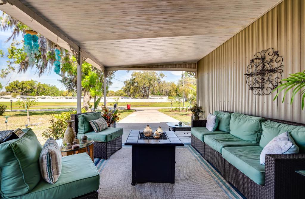 a covered porch with green couches and a table at 27 Mi to The Villages Lush Home with Outdoor Space! in Bushnell