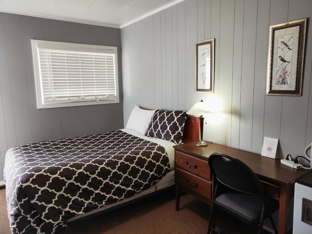 a hotel room with a bed and a desk and a desk at Melsask Motel in Melville