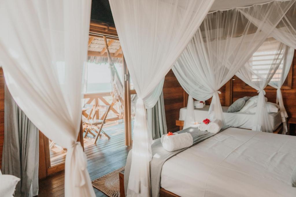 a bedroom with a bed with white drapes at Vila Vento in Atins