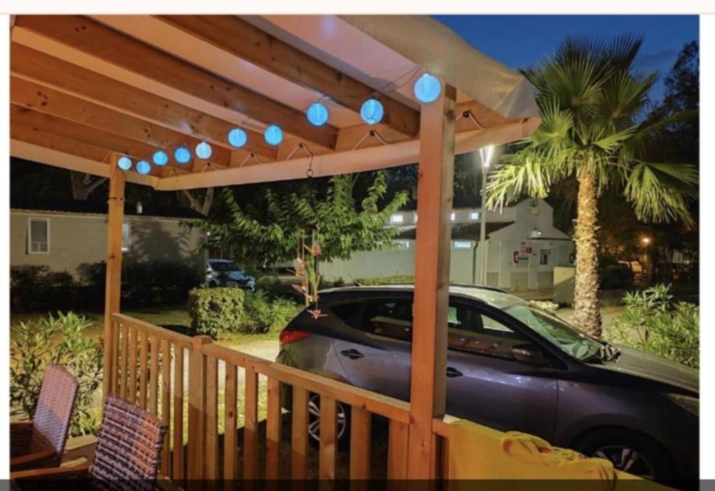 une pergola en bois avec une voiture garée sous celle-ci dans l'établissement Camping marvilla MH 253, à Agde