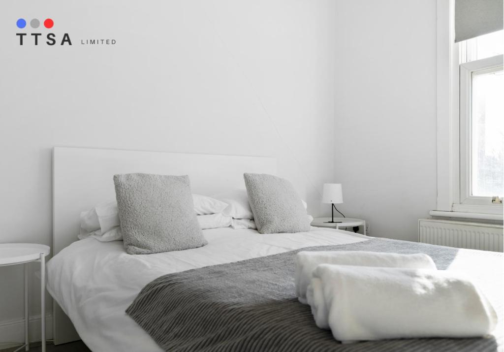 ein weißes Schlafzimmer mit zwei Betten und einem Fenster in der Unterkunft 1-Bedroom Apartment near East Croydon Station - 2 in South Norwood