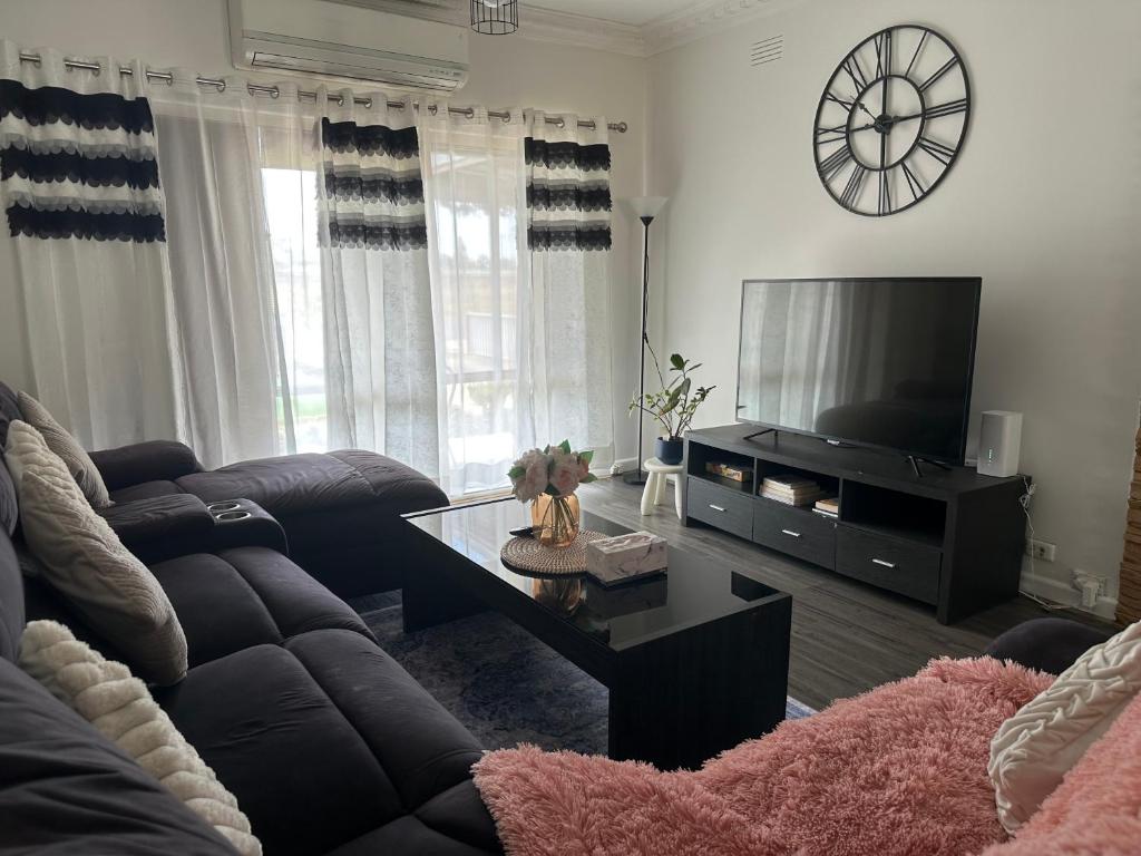 a living room with a couch and a tv at Werribee 3 BR Holiday Home in Werribee