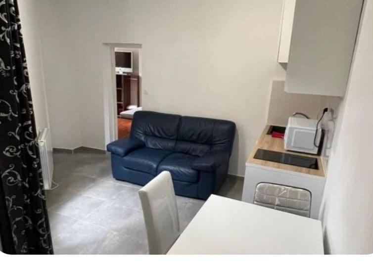 a living room with a blue couch and a kitchen at Beau 2-pieces rch très proche de Paris in Gentilly