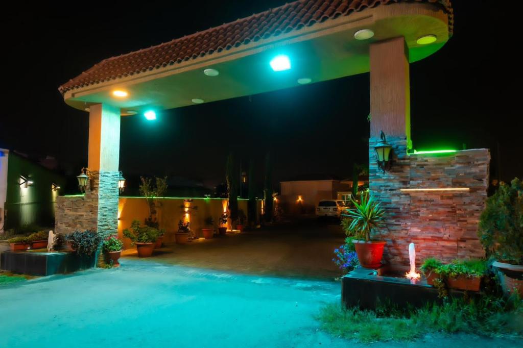 - un patio avec des lumières vertes la nuit dans l'établissement شاليهات بالي, à Jilhayah