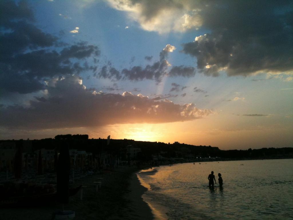 two people standing in the water at sunset at Appartamento Anna Maria in San Vito lo Capo