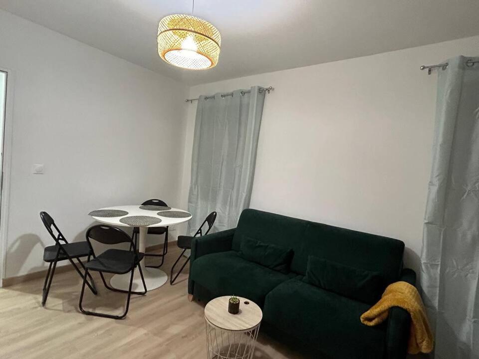 a living room with a green couch and a table at 4 personnes - Proche Centrex et Disneyland in Noisy-le-Grand
