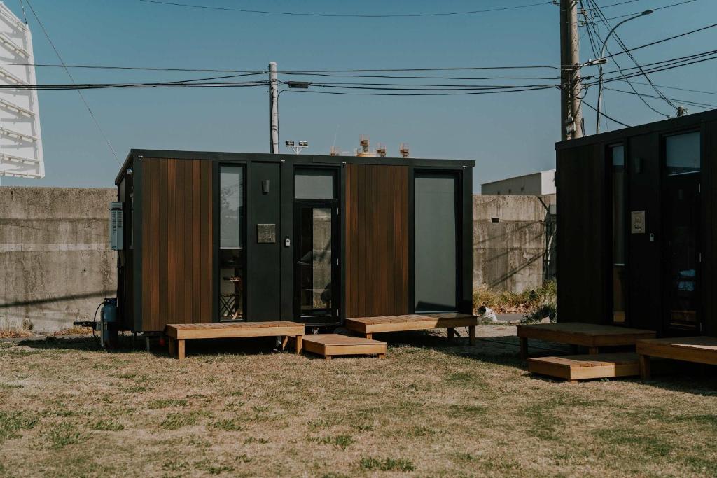 a tiny house with benches next to a fence at Fulu Dragon Boat Camping House 2 by Tiny Away in Ch'iao-t'ou