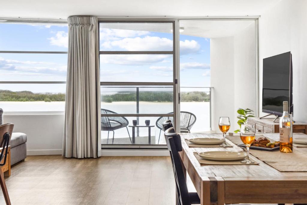 a dining room with a table and a large window at Pumicestone Passage Waterfront Escape in Caloundra