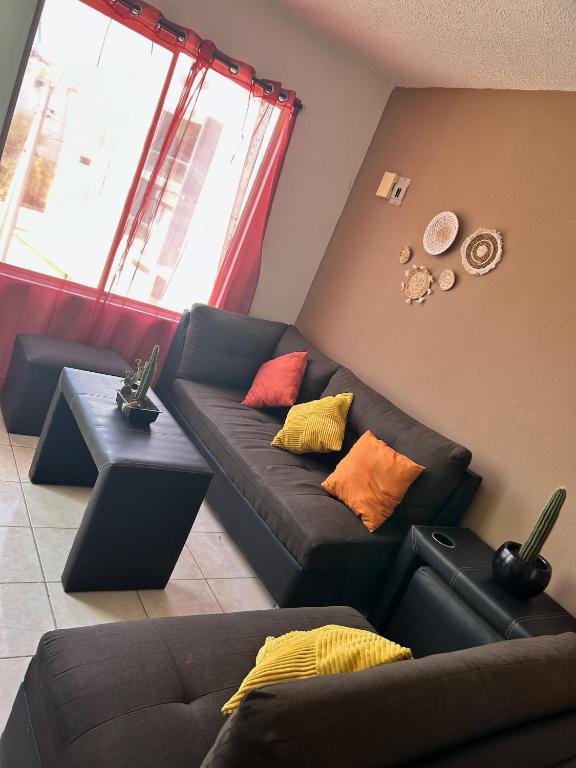 a living room with a black couch with colorful pillows at Departamento 5 Economico Arroyo in Tuxtla Gutiérrez