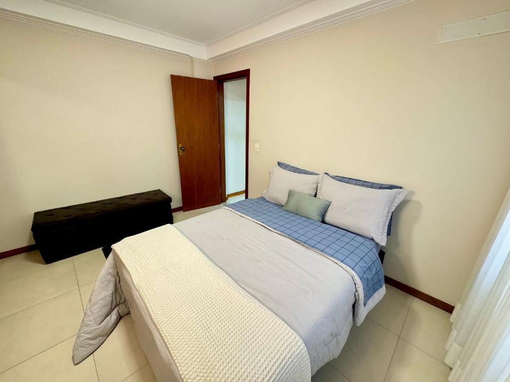 a bedroom with a bed with blue and white pillows at Conforto e Praticidade no Centro de Friburgo! in Nova Friburgo
