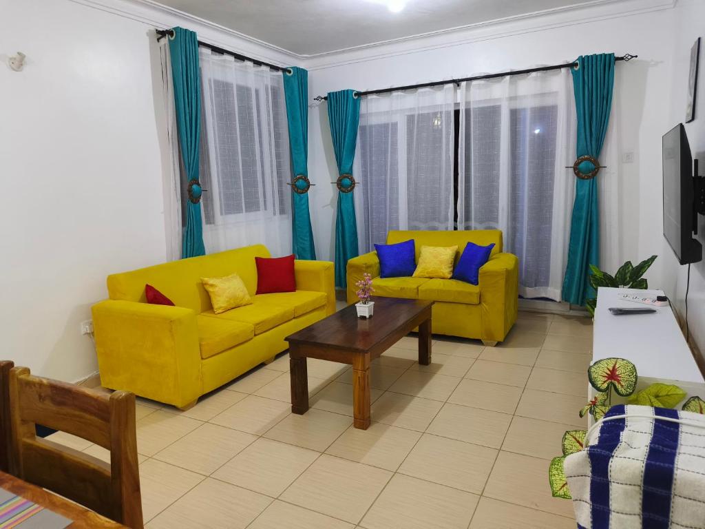 a living room with two yellow couches and a coffee table at NimKai Gold Place in Mtwapa